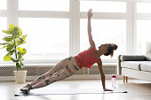 Fit millennial female doing side plank at home