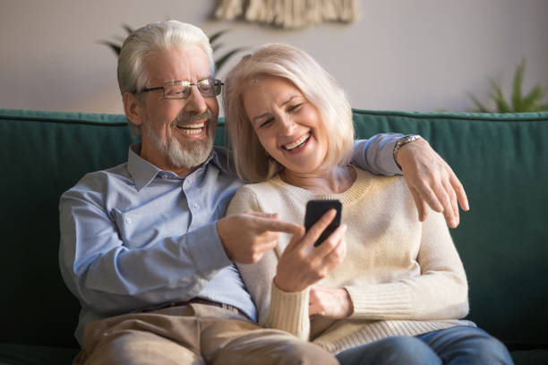istock Happy old couple holding smartphone looking at cellphone screen laughing 1173666465