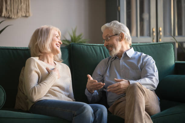 istock Happy senior old couple relaxing talking laughing sitting on couch 1173666981