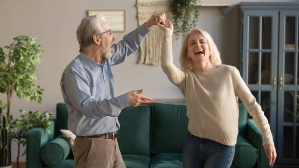 joyful active old retired romantic couple dancing in living room - grandparent retirement senior adult healthy lifestyle imagens e fotografias de stock