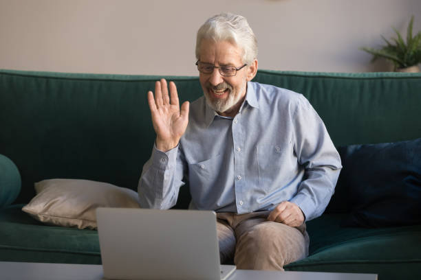 istock Happy old man waving hand talking to webcam make videocall 1173667013