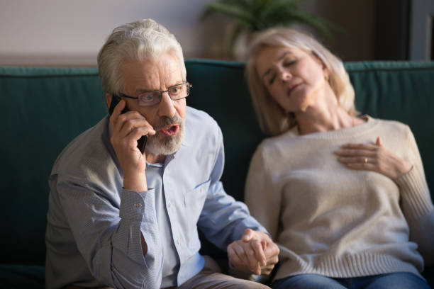 istock Elder husband calling 911 on phone for wife heart attack 1173667032
