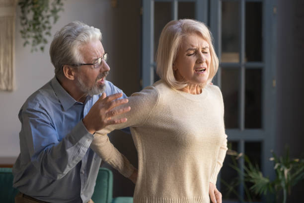 starszy mąż pomaga w średnim wieku żona czuć nagłą ból pleców - worry stones zdjęcia i obrazy z banku zdjęć