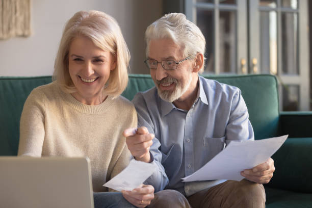 pares velhos felizes que pagam contas domésticas em linha usando o app de computador - pension currency senior adult couple - fotografias e filmes do acervo