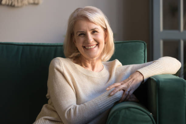 istock Happy middle aged woman looking at camera sit on sofa 1173667057