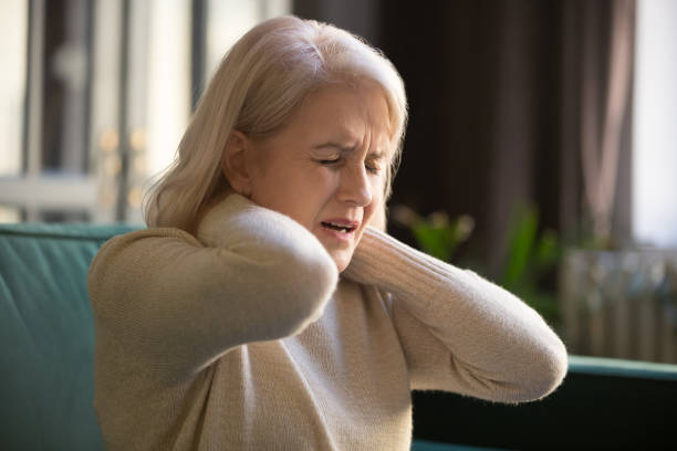 stanca sconvolta vecchia donna anziana che sente il concetto di dolore al collo rigido - collo umano foto e immagini stock