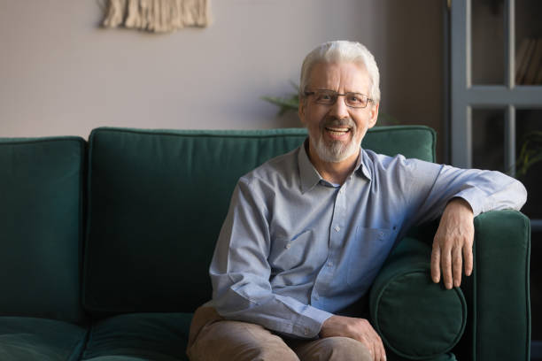 istock Smiling senior man sit on sofa in living room, portrait 1173667080