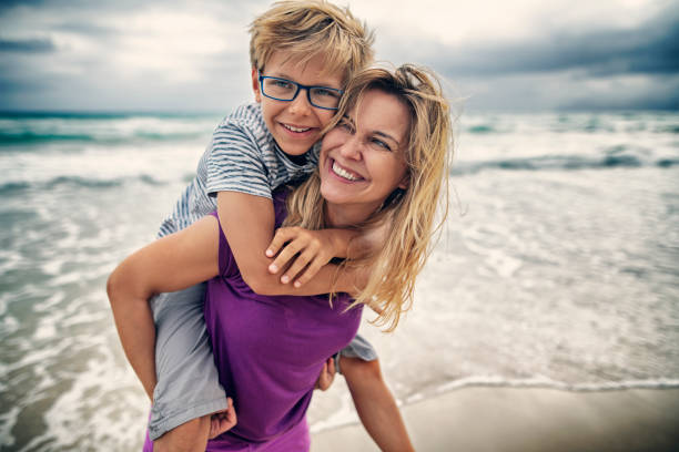 Mother and son enjoying piggyback ride on beach