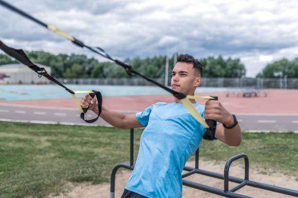 istock Athletic man athlete training on loops, active straps traction, summer city training, motivation for doing fitness sports workout. Active lifestyle young people, powerful stylish man trainer teacher. 1173671500