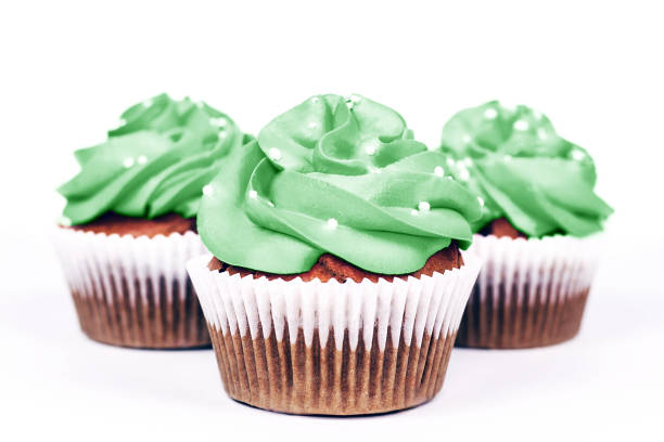Three cupcakes with icing in trendy neo mint color on white background. Close-up.