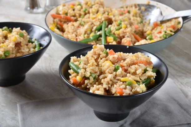 Fried rice with vegetables Closeup of a bowl of fried rice next to the serving pan chinese cuisine fried rice asian cuisine wok stock pictures, royalty-free photos & images