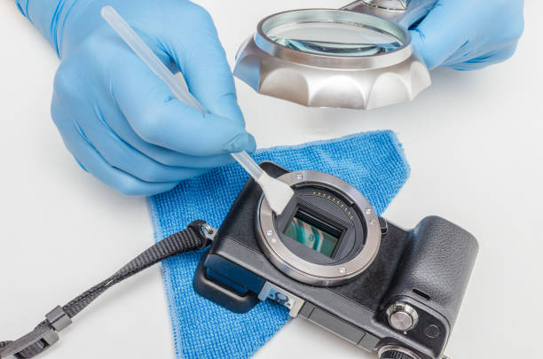 istock Cleaning the digital camera matrix. Digital camera service. The master in gloves under a magnifying glass cleans the matrix of a digital camera from contamination using a washing mop 1173680309