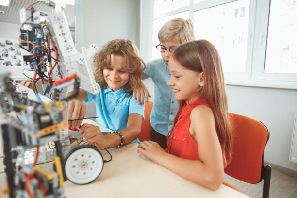 istock Robotics. Children sitting having class making robots smiling excited teamwork 1173696778