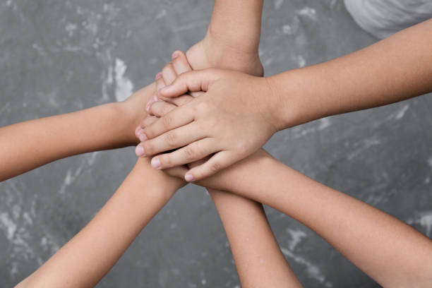 istock children hand together in a circle with palms down on gray background 1173704077