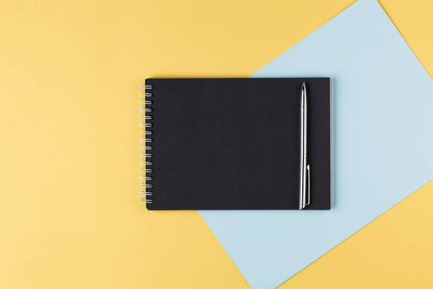istock notebook with black paper and pen on a yellow background top view 1173704131