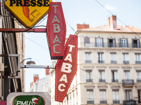 Picture of a tobacconist sign, traditional from France, in front of a store selling tobacco products such as cigarettes or cigars. They are called buralistes or marchand de tabac in France