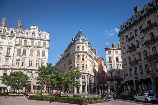 Picture of people walking in the streets of Lyon, France, on a pedestrian square, Place des Jacobins, with some typical French Haussman architecture buildings, as well as shops and other commercial boutiques