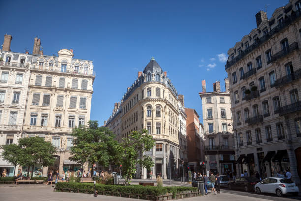 Pedestrians walking on Place des Jacobins in Lyon, France, facing a Haussmann style building and some commercial shop and stores stock photo