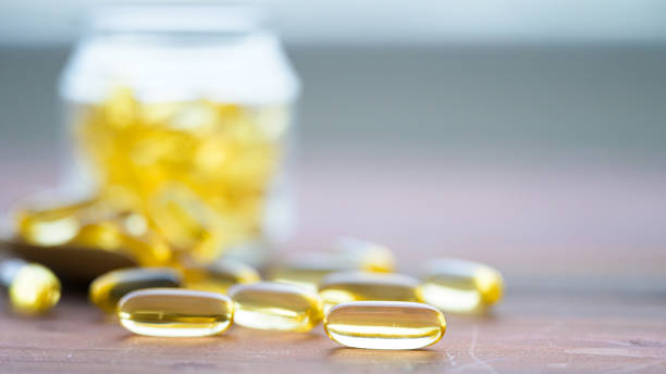 Pile of capsules Omega 3 in glass bottle on wood table Pile of capsules Omega 3 in glass bottle on wood table omega 3 photos stock pictures, royalty-free photos & images
