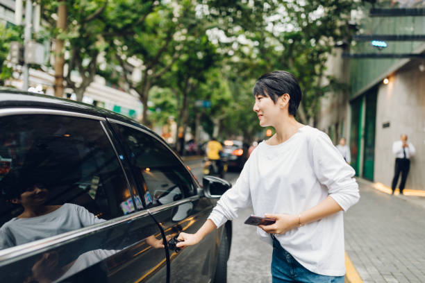 Young Asian woman ordering a taxi ride with mobile app on smartphone in the city. China - East Asia, Shanghai, Crowdsourced Taxi, Taxi, Ordering, Women crowdsourced taxi stock pictures, royalty-free photos & images