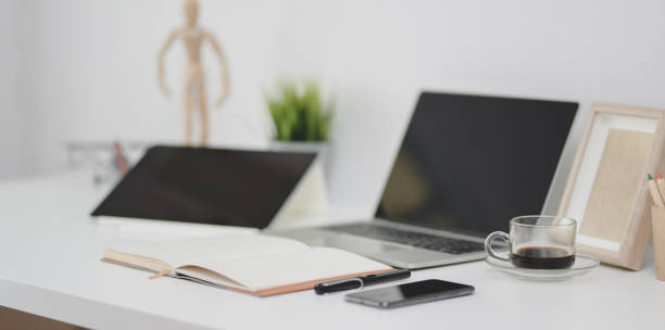 istock Open laptop computer with open notebook, office supplies and decorations on white office desk 1173721049