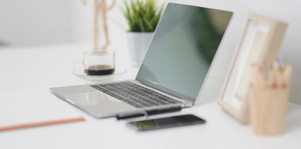 istock Open laptop computer with office supplies and decorations on white office desk 1173721075