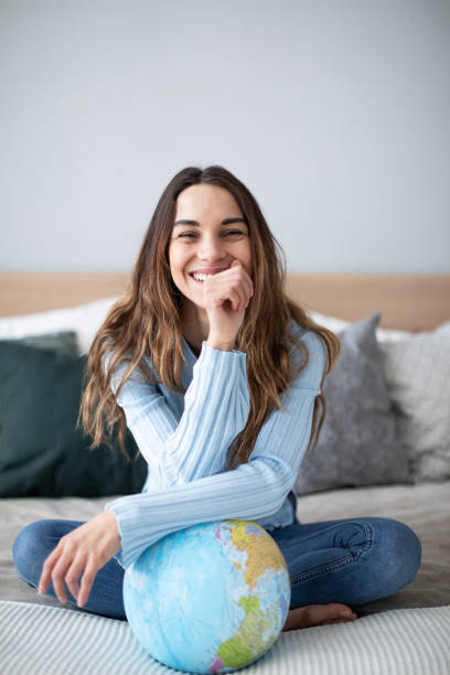 istock Joyful smiling woman indoors with a globe looking at the camera. 1173721315
