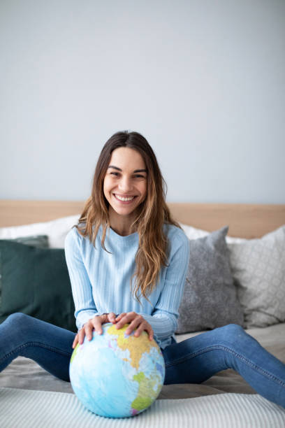 istock Joyful smiling woman indoors with a globe looking at the camera. 1173721950
