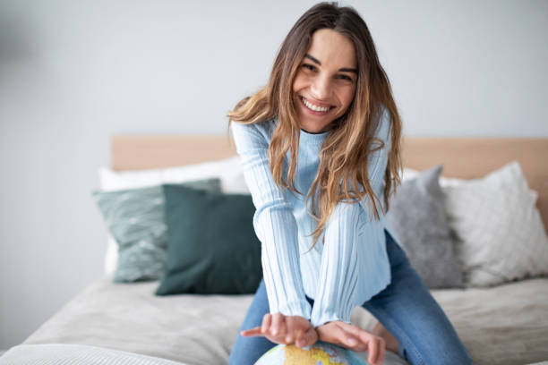 Joyful smiling woman indoors with a globe looking at the camera.