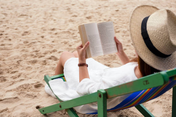 istock woman lying down and reading book on the beach chair 1173726657