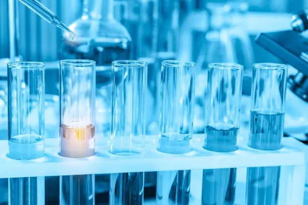 Photo of scientist with equipment and science experiments, laboratory glassware containing chemical liquid for research or analyzing a sample into test tube in laboratory