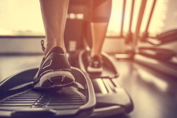 Closeup leg of cardio workout on an elliptical.people working out on an elliptical trainer in gym.Back view stock photo