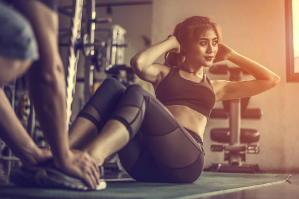 mujer fitness haciendo ejercicios de sit-ups. mujer haciendo entrenamiento abdominal con entrenador personal - sit ups fotografías e imágenes de stock