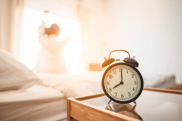 zbliżenie budzika w łóżku po przebudzeniu, światło słoneczne rano. - alarm clock zdjęcia i obrazy z banku zdjęć