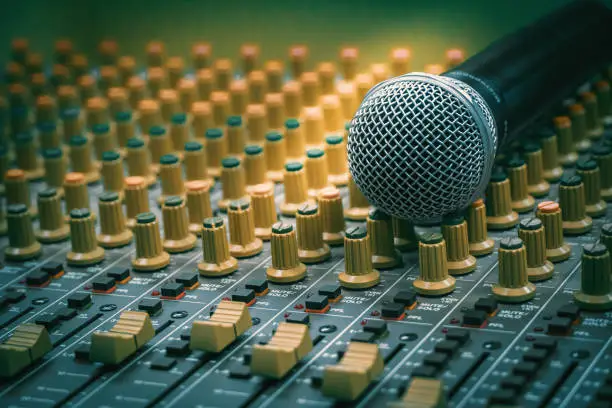 Photo of Microphone placed together with the audio mixer in the recording room, vintage film style