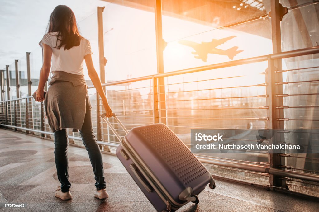 Young woman pulling suitcase in  airport terminal. Copy space Airport Stock Photo