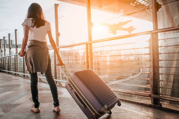 Young woman pulling suitcase in  airport terminal. Copy space stock photo
