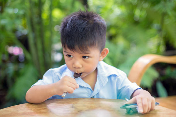 ładny mały chłopiec siedzący jedząc ciasto czekoladowe w ogrodzie - 5519 zdjęcia i obrazy z banku zdjęć