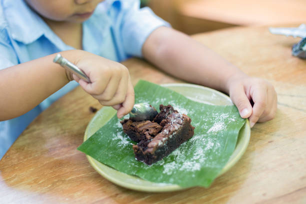 nette kleine junge sitzen essen schokoladenkuchen in einem garten - 5547 stock-fotos und bilder