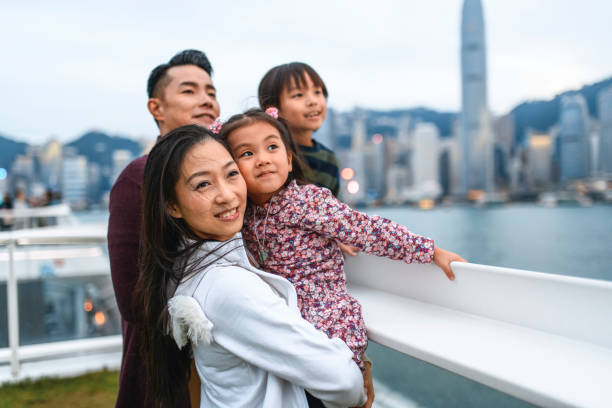 smiling young chinese family enjoying hong kong at dusk - harbour city imagens e fotografias de stock