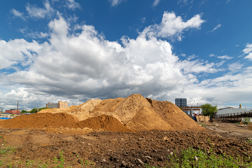 Dirt mound on a background of blue sky with white clouds.