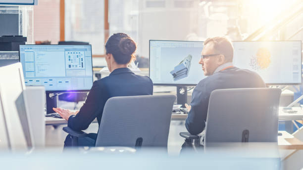 istock Back View of Team of Technology Engineers Working on Desktop Computers in Bright Sunny Office with Sun Flare. Screens Show IDE / CAD Software, Implementation of Machine Learning, Neural Networking 1173740450
