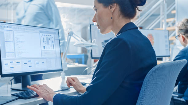 istock Back View of Team of Technology Engineers Working on Desktop Computers in Bright Office. Screens Show IDE / CAD Software, Implementation of Machine Learning, Neural Networking and Cloud Computing 1173740564