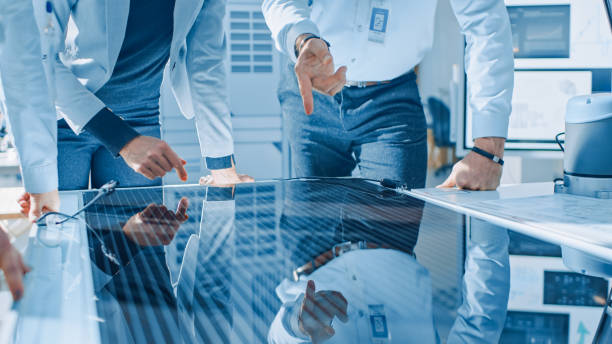 istock Team Meeting of Renewable Energy Engineers Working on an Innovative More Efficient Solar Panel Battery Concept. Group of Specialists Gathered Around Table, Solving Problems. Bright Research Facility 1173740574