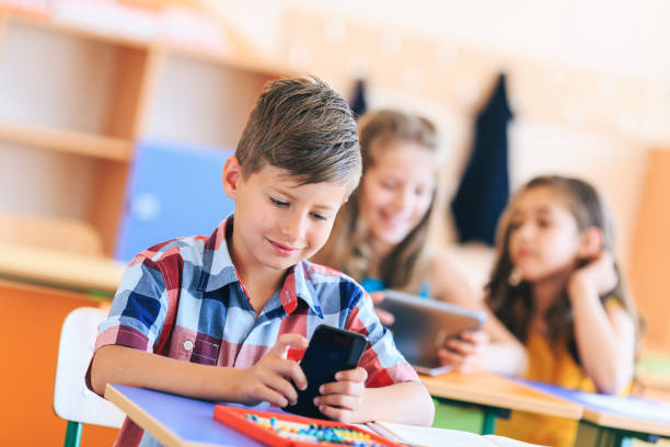 istock Schoolboy use a mobile phone in the classroom 1173741384