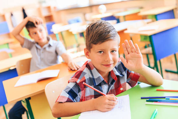 istock School kids in classroom raise hands 1173741393