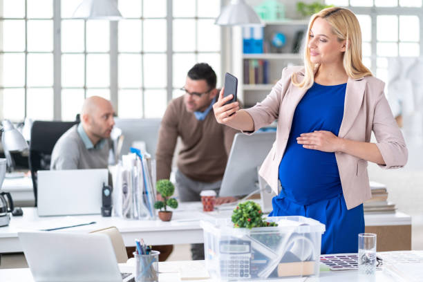 istock Smiling pregnant woman taking selfie at workplace 1173741406