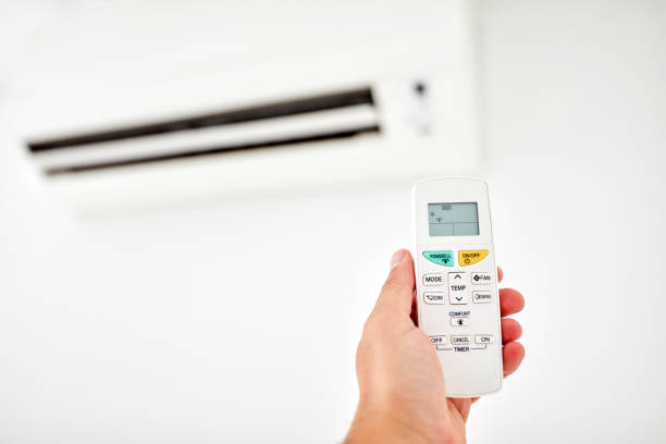 istock Modern air conditioner unit with a hand holding a remote. 1173742581