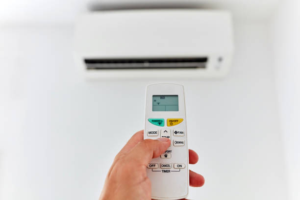 istock Modern air conditioner unit with a hand holding a remote. 1173742643