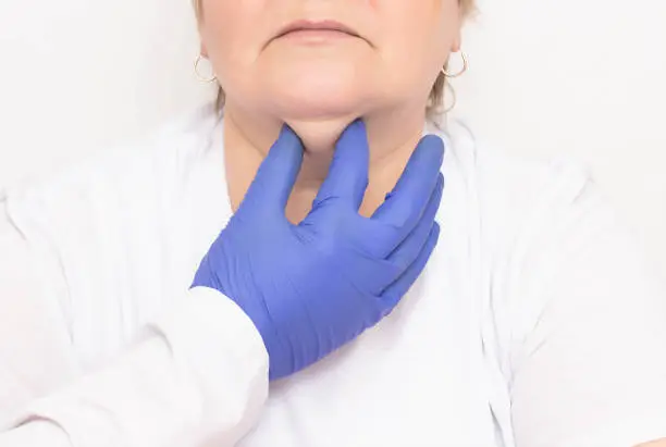 A plastic surgeon examines an aged woman to tighten and get rid of wrinkles and double chins, white background, cosmetologist